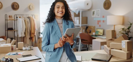 Una mujer sonriendo con una tablet en la mano
